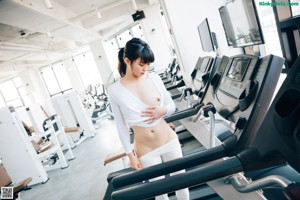 A woman is running on a treadmill in a gym.