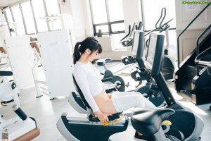 A naked woman doing pull ups in a gym.