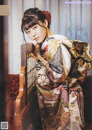 A woman in a red and white kimono standing next to a fence.