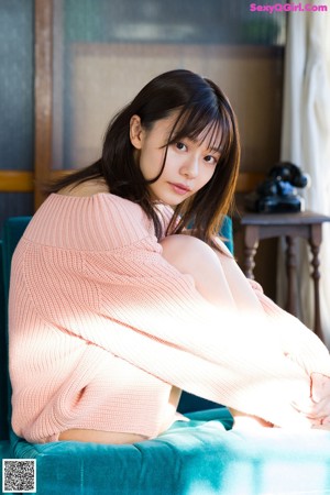 A young woman sitting at a table with an orange.