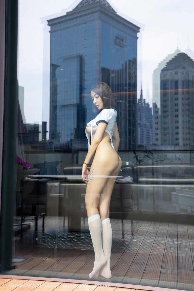 A woman standing in front of a window with a view of a city.