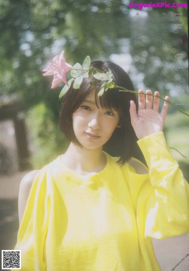 A woman in a yellow dress holding a flower in her hand.