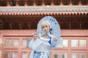 A woman in a white and blue dress holding an umbrella.