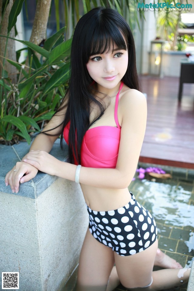 A woman in a pink top and black and white polka dot shorts.