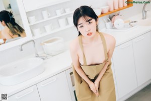 A woman standing in front of a sink in a kitchen.