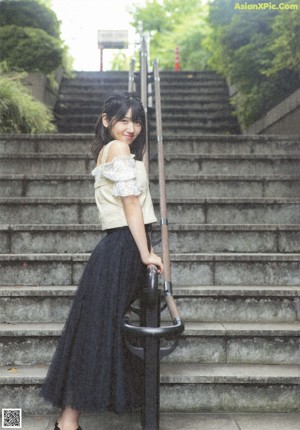 A woman in a white dress standing in front of some stairs.