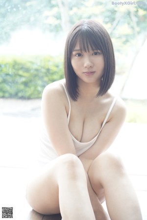 A woman in a white lingerie sitting on a bed.