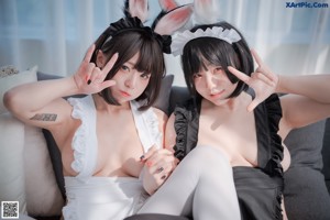 Two asian women dressed in bunny ears and lingerie posing for the camera.