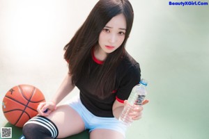 A woman sitting on a basketball on a court.