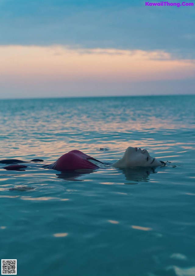 A woman floating in the ocean with her head above the water.