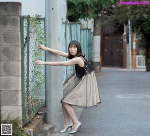 A woman in a pink dress standing in front of a pink wall.