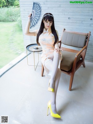 A woman in a white lingerie sitting on a chair.