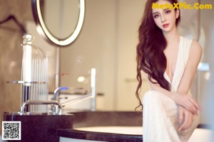 A woman in a white dress posing in a bathroom.