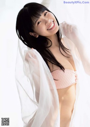 A woman in a pink bikini standing in front of a window.