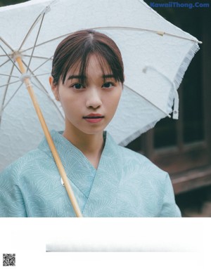 A woman in a kimono standing in front of a window.