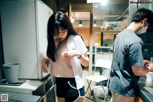 A woman sitting on a chair in front of a microwave.