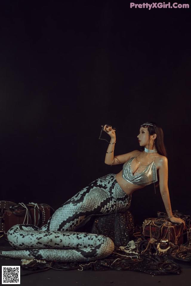 A woman in a mermaid costume sitting on the ground.