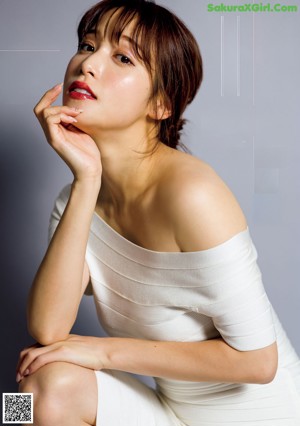 A woman laying on a bed in a white shirt.