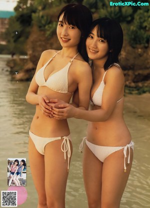 Two women in bikinis standing in the water at the beach.