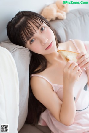 A woman with long black hair leaning against a wall.