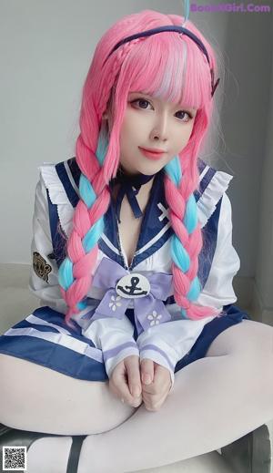 A woman with pink hair wearing a sailor outfit.