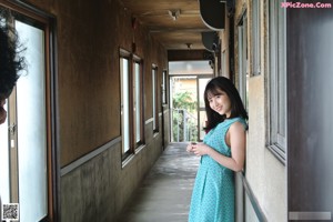 A woman in a white shirt and blue skirt standing next to a fence.