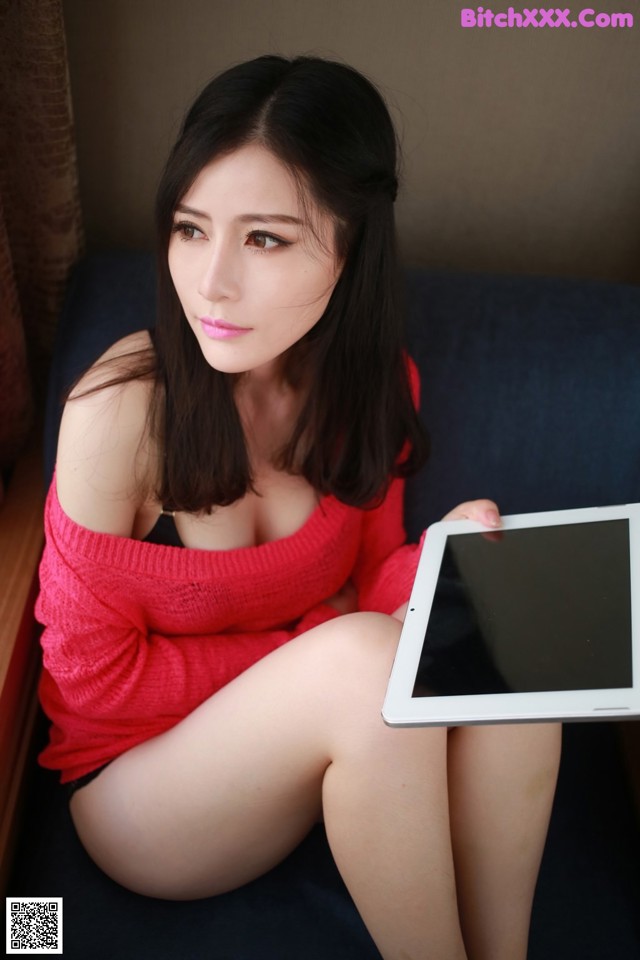 A woman sitting on a couch holding a tablet computer.