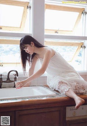 A woman standing in a kitchen reaching for a bowl of food.