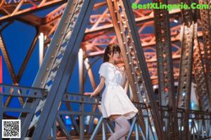 A woman in a white dress standing on a bridge.