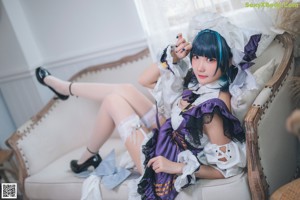 A woman in a maid outfit is sitting on the floor.