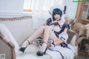A woman in a maid outfit is sitting on the floor.