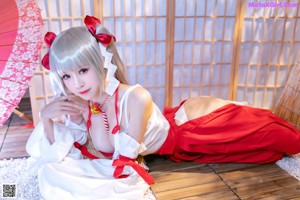 A woman in a red and white dress sitting on a wooden floor.